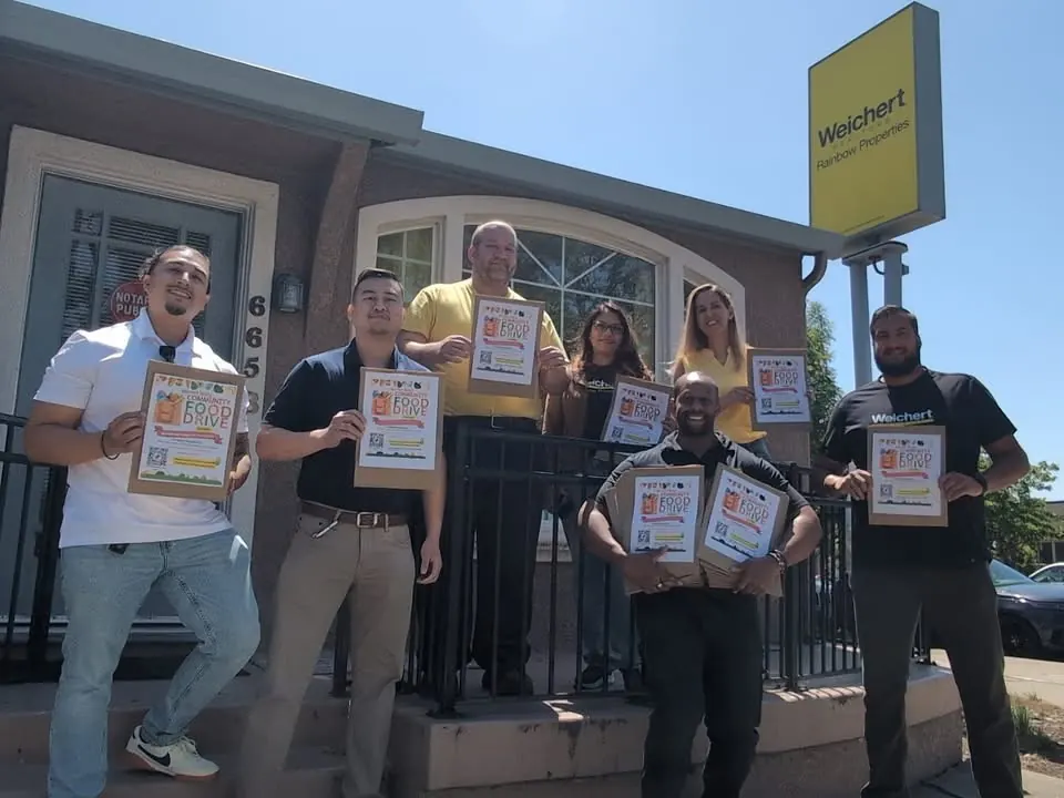 Rainbow Properties team holding food-drive flyers outside the office
